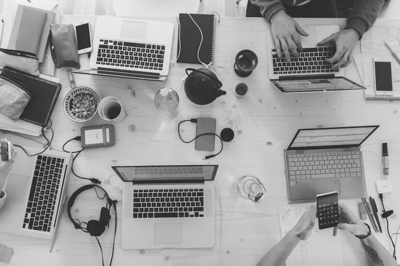 People collaborating around a table with laptops and notebooks